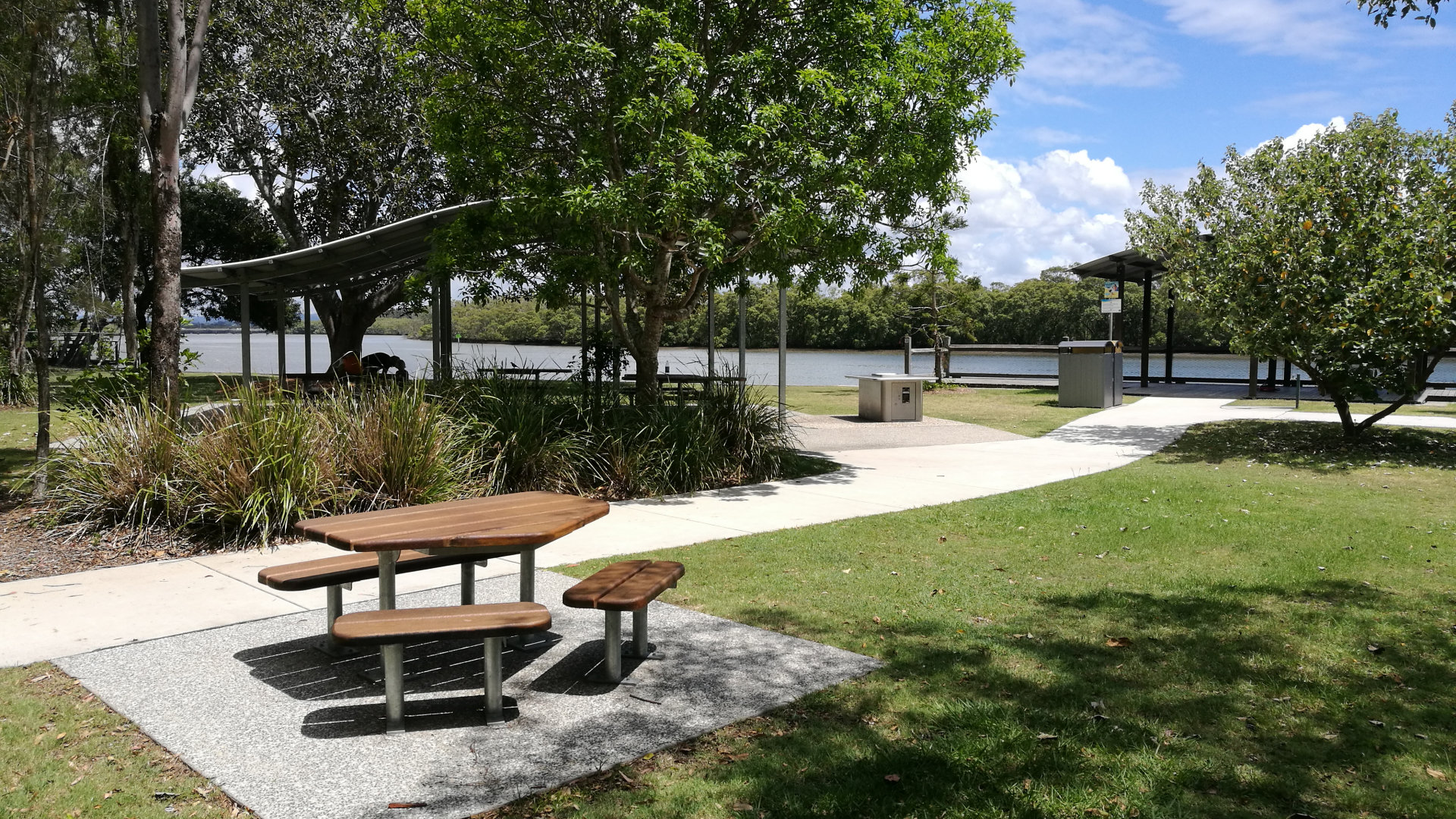 Park area at Tinchi Tamba Wetlands with picnic tables, BBQ, and the North Pine River in the background. Tinchi Tamba is named after the Aboriginal words for ibis and mangroves