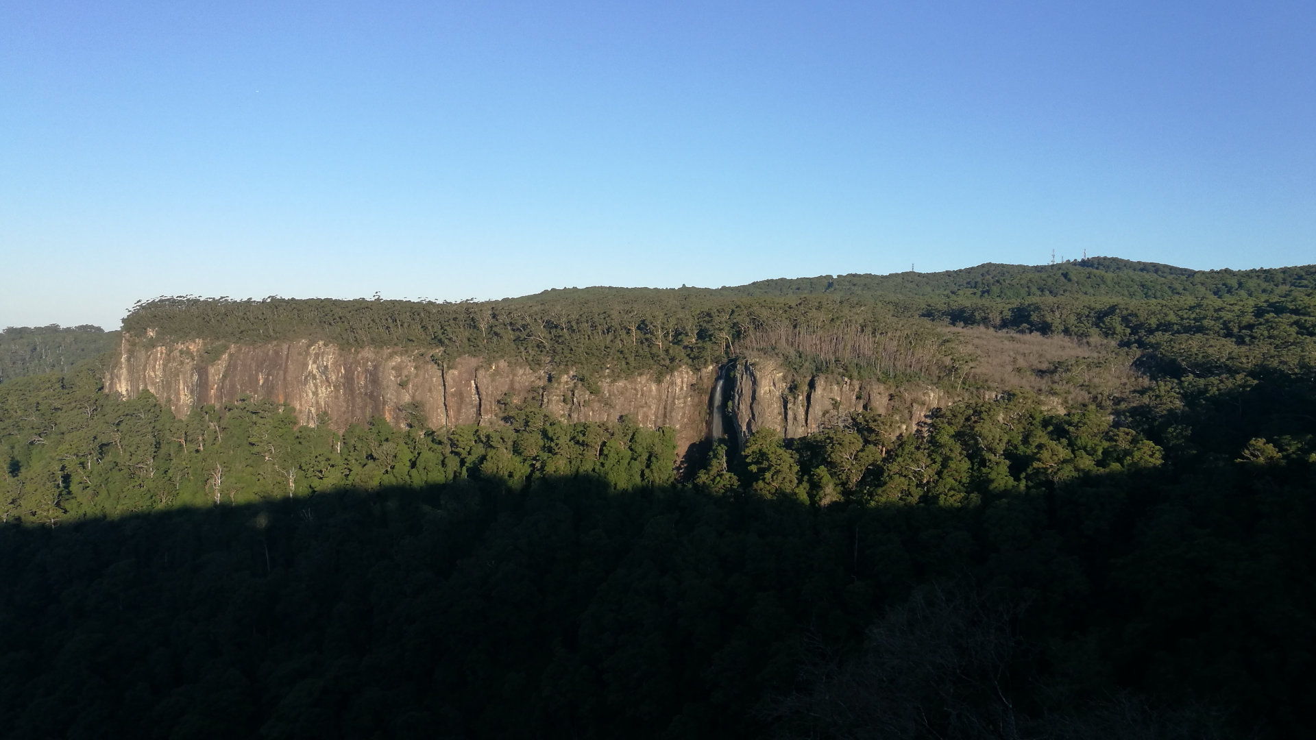 View of the rock wall across Canyon Lookout, located in Springbrook with views across the canyon, and down the valley through to the Gold Coast in the distance