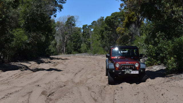 Wide dark sand track, Jeep Wrangler on the right hand side, on the access track to the Ocean Beach on Bribie Island
