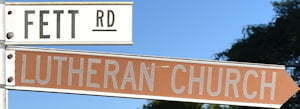 Brown sign for Lutheran Church, white sign for Fett Rd