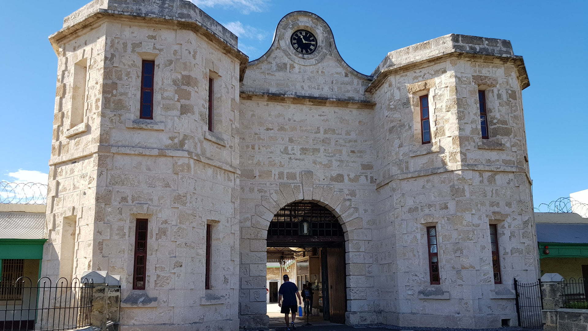 Entrance arch to the Fremantle Prison, made of stone with a central arch opening with a clock at the top and flanked by two octagonal towers