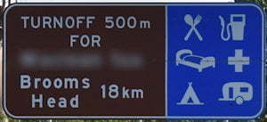 Brown sign for Brooms Head, 18km, turn off 500m for