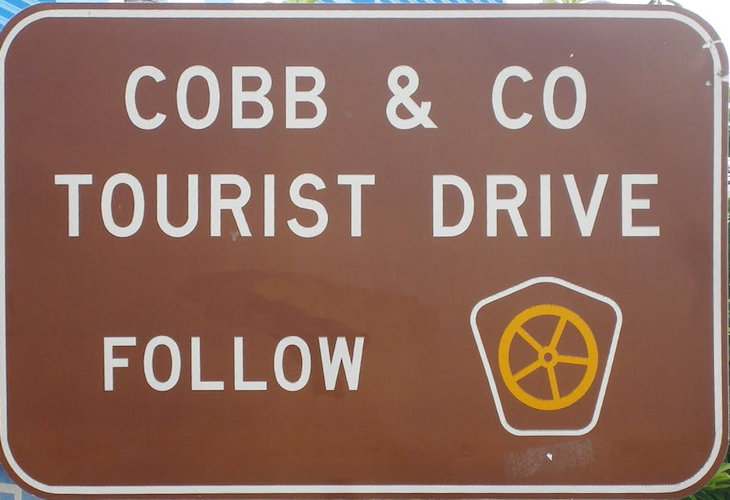Brown sign for Cobb & Co Tourist Drive, with the wagon wheel symbol for the tourist route
