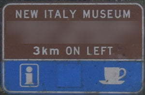 Brown sign for New Italy Museum, 3km on left, blue sign with symbols for information and cafe