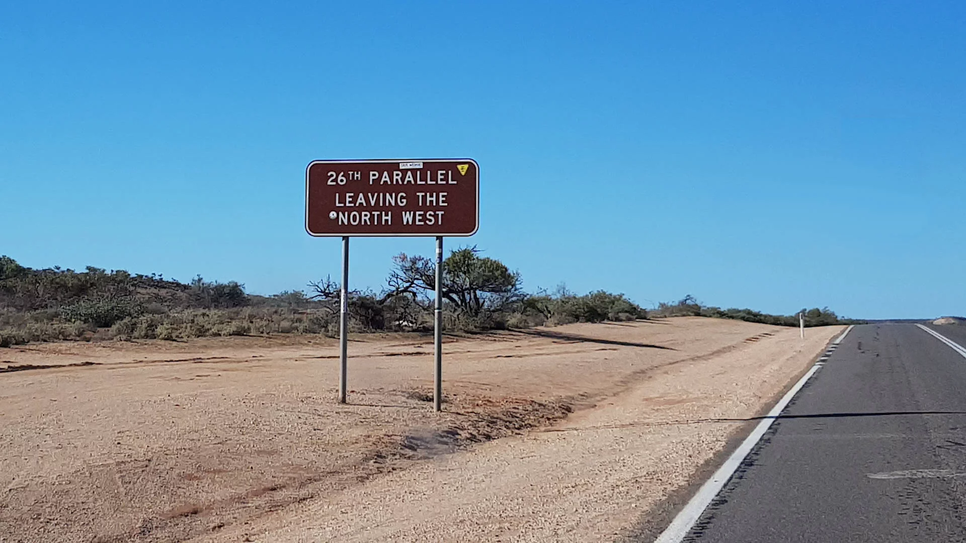Brown sign at the 26th Parallel on the edge of the North West region in Western Australia