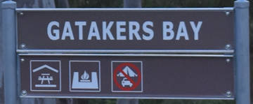 Brown sign for Gatakers Bay, symbols for sheltered picnic tables, BBQs, no camping