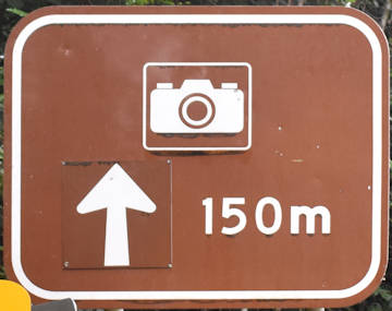 Brown sign for a lookout with camera symbol, 150m