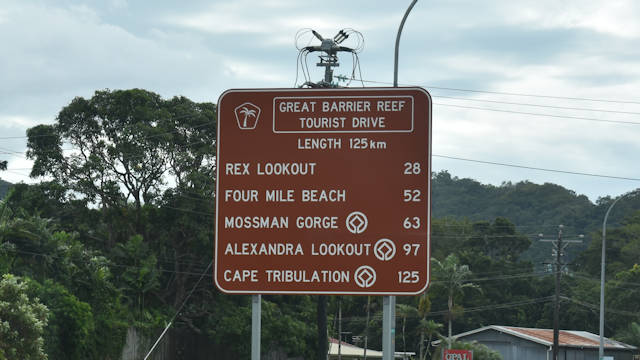 Brown sign for Great Barrier Reef Tourist Drive, length 125km, Rex Lookout 28km, Four Mile Beach 52km, Mossman Gorge 63km, Alexandra Lookout 97km, Cape Tribulation 125km