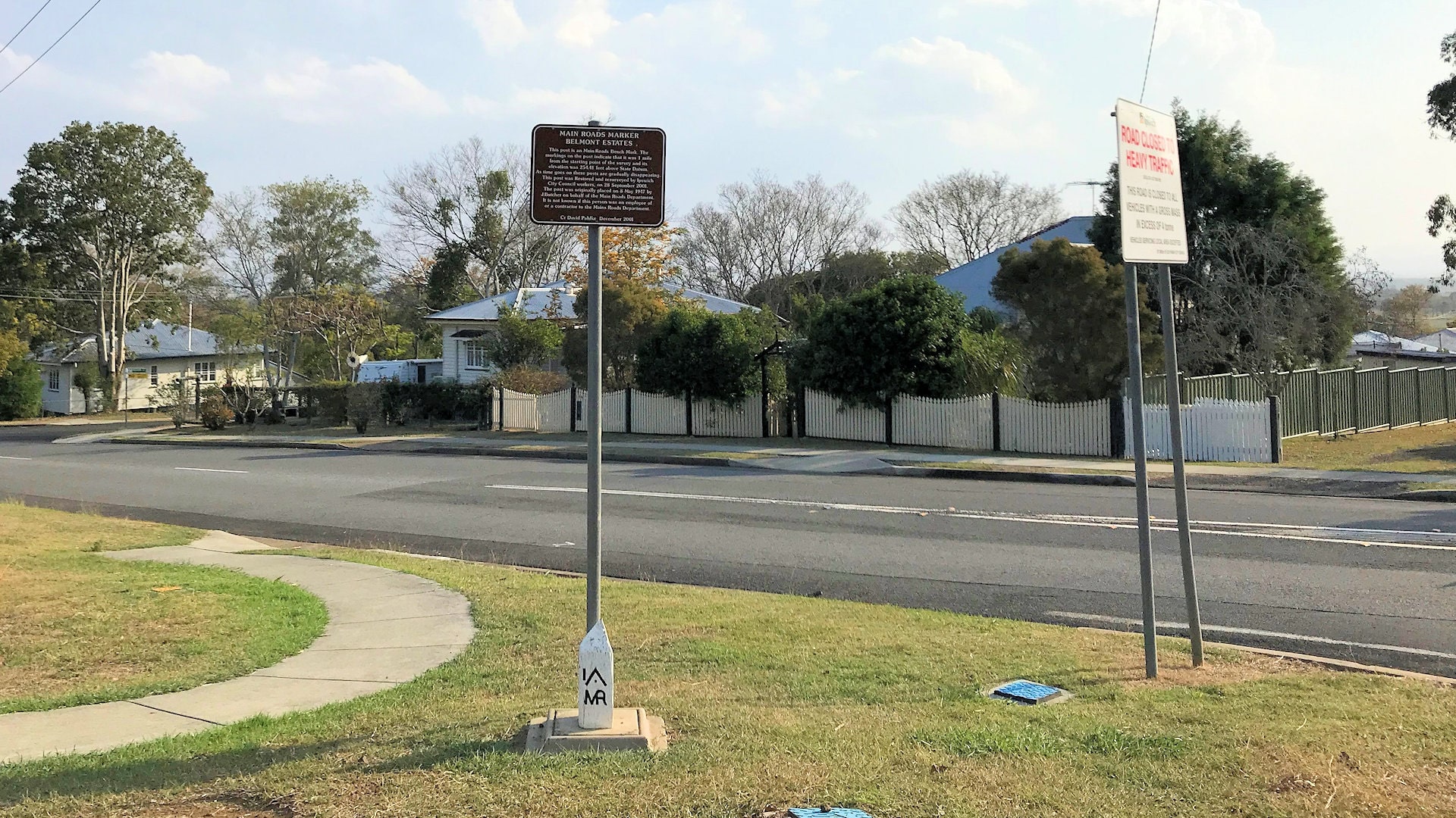 Mile marker on the corner of a road with a brown sign above it