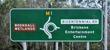 Brown sign for Boondall Wetlands, green sign for Brisbane Entertainment Centre
