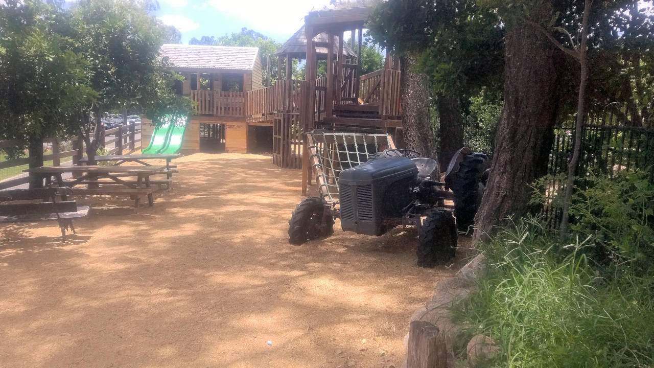 Playground with wooden fort, slide, old tractor