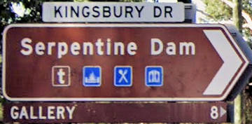 Brown sign for Serpentine Dam with symbols for food, toilets, white sign for Kingsbury Rd, brown sign for Gallery 8km