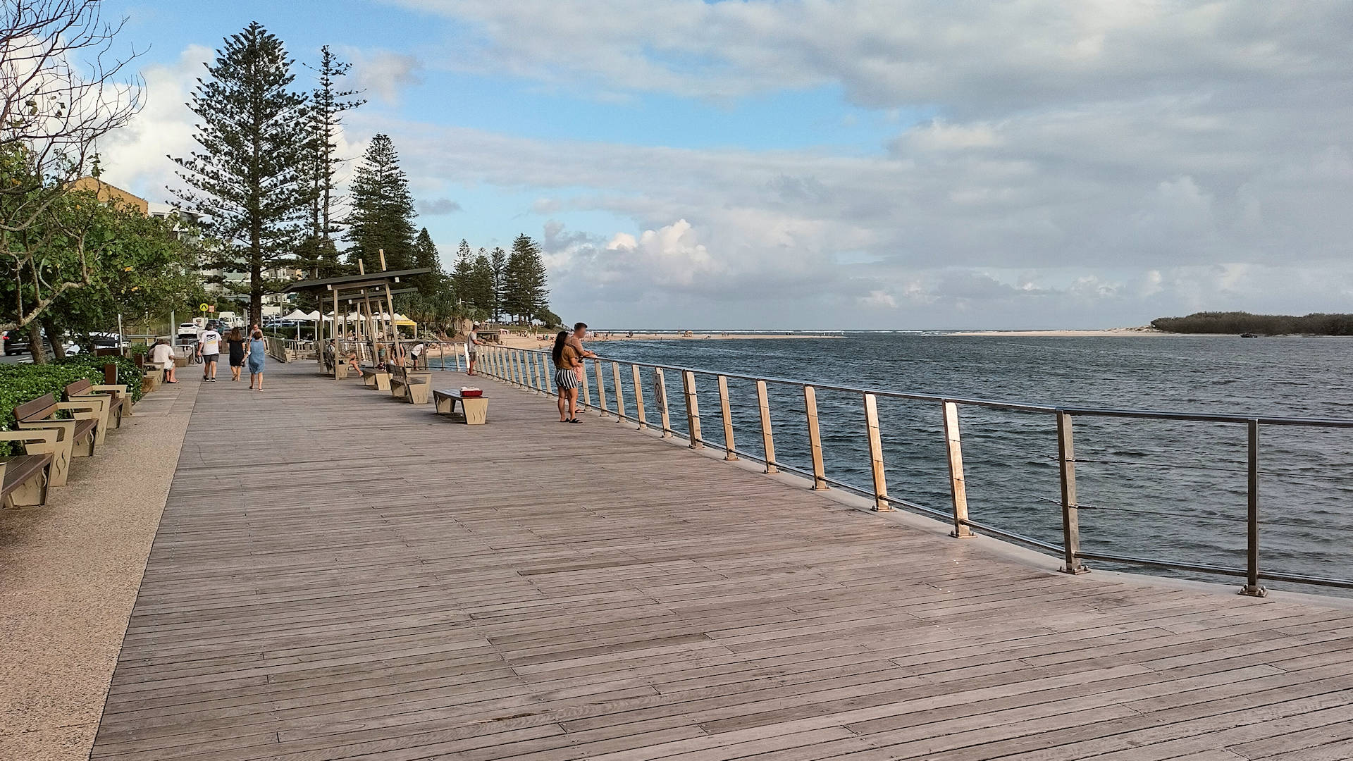 Boardwalk on the edge of a wide river looking towards the mouth to the ocean