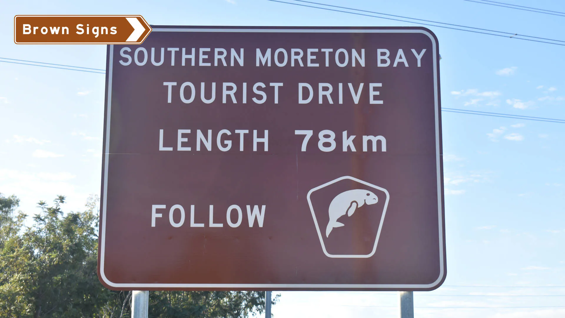 Brown sign showing the start of the Southern Moreton Bay Tourist Drive, length of 78km and a tourist drive symbol of a dugong