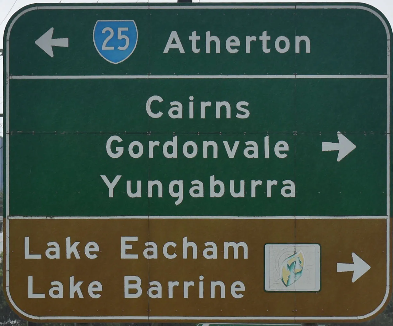 Brown sign for Lake Eacham and Lake Barrine, green sign for Atherton, Cairns, Gordonvale, and Yungaburra